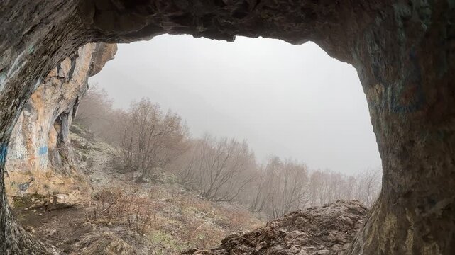 Seeking shelter in a cave and observing from a protected spot during extremely windy and rainy weather.