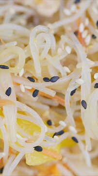 Vibrant noodle salad. Delicate rice noodles with colorful vegetables and sesame seeds. Appetizing street food style rice noodle salad with vibrant vegetables and glossy dressing