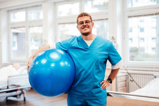Physiotherapist in scrubs with exercise ball in physiotherapy clinic