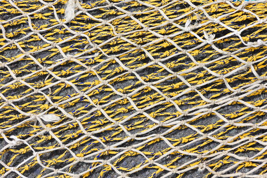 Yellow and white fishing net  with signs of wear, textured background.