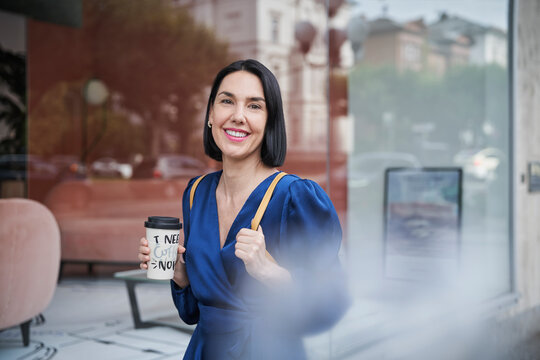 Smiling person with coffee to go in city setting