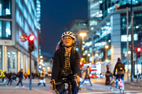 Urban cyclist commuting at night in London with city lights