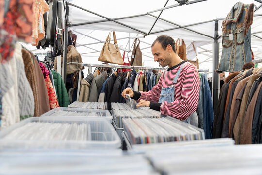 Customer browsing vinyl records at flea market smiling outdoors