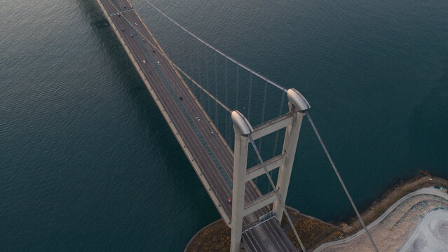 Aerial view of the Tsing Ma Bridge's majestic span over the water, a symphony of steel and concrete against the dark teal sea, Hong Kong, Hong Kong.