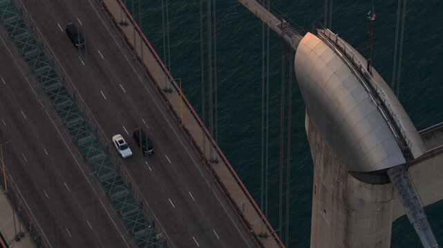 Aerial view of vehicles traversing the Tsing Ma Bridge, its stark concrete contrasting with the dark waters below, Hong Kong, Hong Kong.