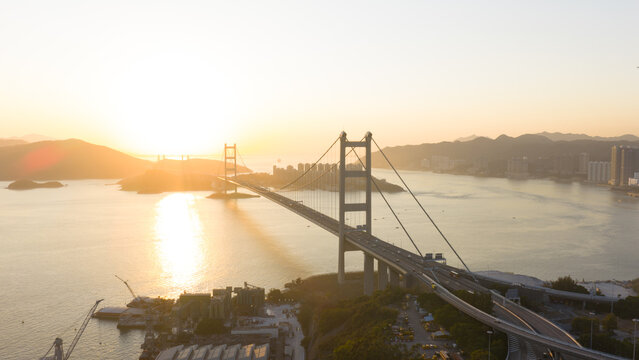 Aerial view of the majestic Tsing Ma Bridge at sunset casting long shadows over the water, Hong Kong, Hong Kong.