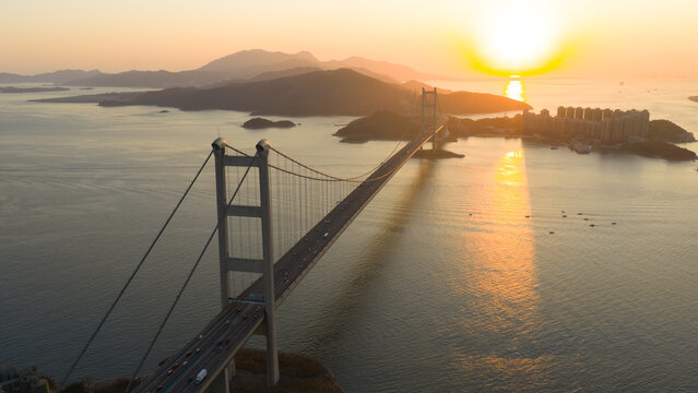 Aerial view of the majestic Tsing Ma Bridge stretching across the tranquil waters as the sun casts a golden glow on the horizon, Hong Kong, Hong Kong.