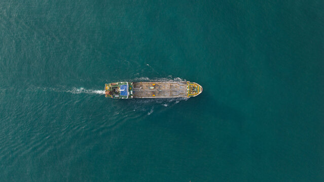 Aerial view of a lone vessel cuts through the tranquil, turquoise waters, leaving a foamy wake, Tambon Map Ta Phut, Chang Wat Rayong, Thailand.