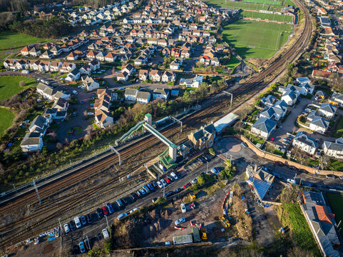 Aerial view of the railway tracks cutting through the heart of the town, with the station and footbridge providing a focal point amidst the houses, Dunbar, Scotland, United Kingdom.