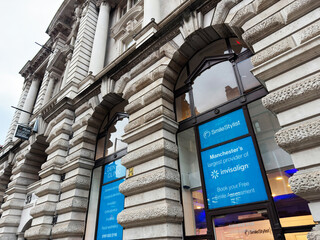 Naklejka premium Manchester street scene with grand stone building housing Smile Stylist Dental Clinics and Invisalign signage