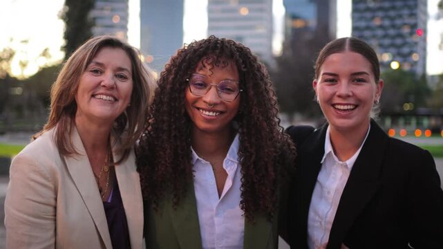 Three diverse women confidently smiling together, showcasing camaraderie and unity in a professional context, embodying teamwork and friendship among colleagues in a supportive atmosphere.