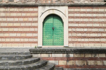 Stone and Brick Wall with Ancient Architectural Detail and Decorative Metal Historical Door and Stone Staircase