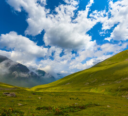 Fototapeta premium green mountain ridge in snow under a blue cloudy sky, mountain travel scene