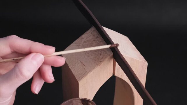 Close-up of applying edge paint to leather belt loops in a workshop setting. Careful manual finishing process that enhances durability and premium look of handmade leather accessories. 