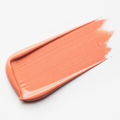 A smear of peach colored lip gloss on a white surface
