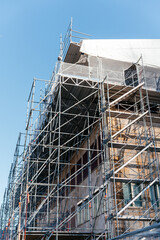 Building facade covered renovation and restoration work. Urban construction and infrastructure development concept highlighting progress, engineering, and property improvement.