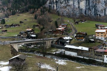 Scenic alpine village with traditional houses and green pastures set against dramatic mountains and rocky cliffs in a peaceful rural landscape. © Христя Сидор