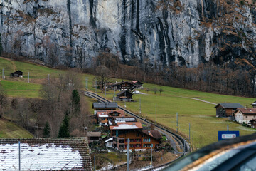 Scenic alpine village with traditional houses and green pastures set against dramatic mountains and rocky cliffs in a peaceful rural landscape. © Христя Сидор