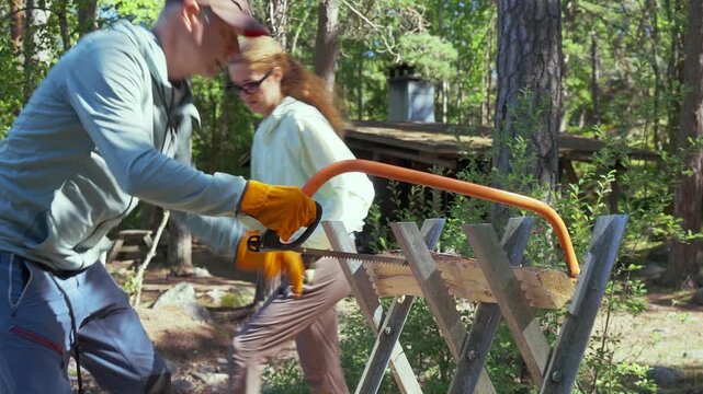 Active couple with backpacks arriving at wooden shelter in Finnish national park. Responsible eco-tourism, wilderness infrastructure and authentic Nordic hiking lifestyle in sunny forest.