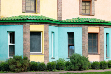 Colorful building exterior with bright turquoise, yellow, and peach walls and green roof