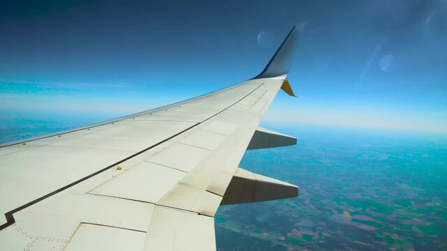Commercial jet flying above patchy farmland. Passenger aircraft cruising over colorful agricultural fields. Airplane gliding over rural mosaic landscape
