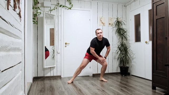 The European athletic man doing alternating side lunges exercise training legs musculs at home. Sportsman does workout with active lunging. Sporty healthy lifestyle. Morning routine. High quality 4K.