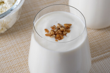 Kefir, buttermilk or yogurt, cottage cheese with granola. Yogurt in glass on white wooden background. Probiotic cold fermented dairy drink. Gut health, fermented products, healthy gut flora concept