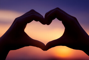  two hands forming a heart shape at sunset