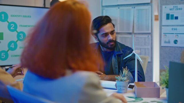 multi-ethnic business people intensely brainstorm focus on monitor,paperwork to strategy for pivotal ESG business shift and agile transformation in office night meeting.ESG policy,volunteer concept