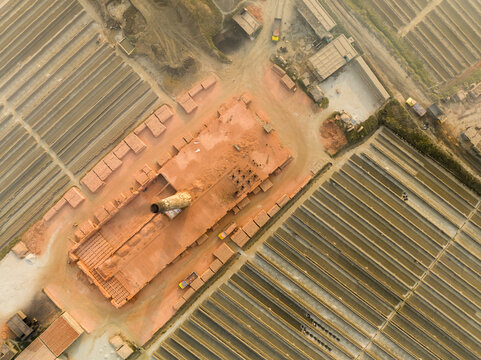 Aerial view of brick kiln with neatly stacked rows of bricks under the sun, casting long shadows, Aminbazar, Dhaka Division, Bangladesh.