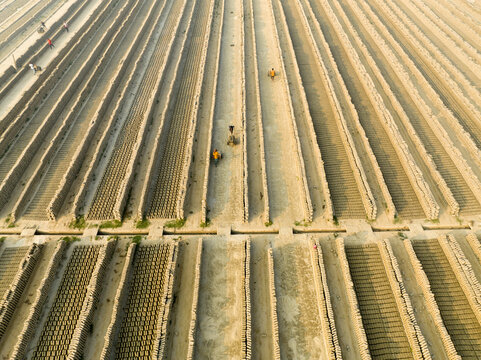 Aerial view of rows of bricks laid out to dry under the sun, creating geometric patterns and earthy textures, Aminbazar, Dhaka Division, Bangladesh.