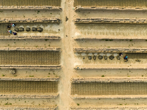 Aerial view of symmetrical patterns of brick fields with workers, a stark contrast of industry and labor, Aminbazar, Dhaka Division, Bangladesh.