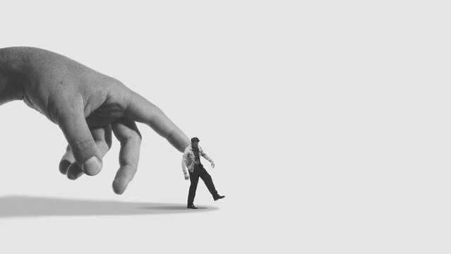 Conceptual mixed media giant hand manipulating small human figure. Concept of algorithm influence, platform dependency, online behavioral control and targeted data driven systems.