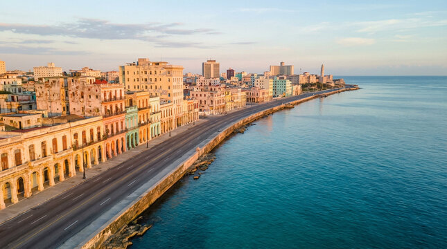 Aerial view of Havana Malecon waterfront boulevard with colonial buildings and calm Caribbean sea at golden hour.
