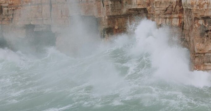 Waves crashing on the cliffs of Polignano a Mare during a storm in Adriatic Sea. Slowmotion 4k 120fps - panning right