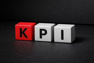 KPI Cubes: Illuminated close-up of a Key Performance Indicator(KPI) concept, represented by three lettered cubes with bold letters, sitting on dark surface.