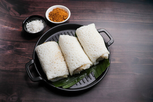 A closeup shot of a traditional Goan Alle Belle coconut pancakes. The crepes are rolled neatly and filled with a rich, dark brown mixture of grated coconut and palm jaggery. popular tea time snack.