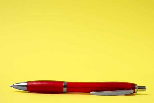 Ein roter Kugelschreiber auf einem gelben Hintergrund mit Freiraum f&uuml;r Weiterverarbeitung