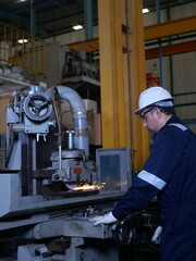 Fototapeta premium Industrial technician operating grinding machine with sparks in manufacturing factory 