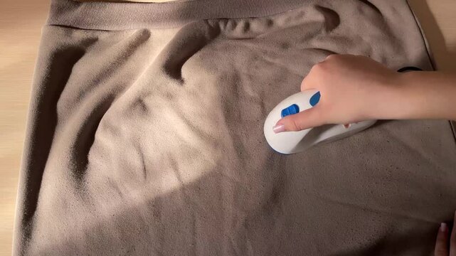 Electric fabric shaver removing lint from fleece sweatshirt close up rotating blades cleaning pills clothing care household garment maintenance