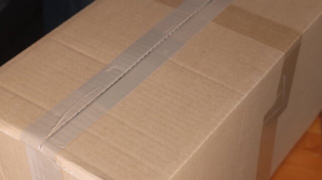 Person opening cardboard box with utility knife