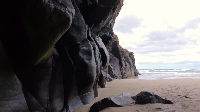 Blick aus der dunklen Felsenh&ouml;hle auf den einsamen Sandstrand und Meer: Dramatischer Lichtkontrast, K&uuml;stenidylle und Naturabenteuer, verborgene Sch&ouml;nheit, Expedition, Landschaft, K&uuml;ste
