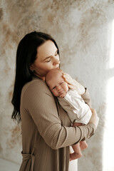 mother and newborn baby at home hugging and kissing, happy mother and baby portrait, mother holding a small baby