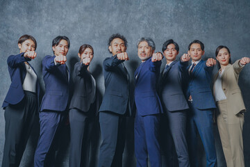 拳を振り上げるスーツを着た様々な世代の男女