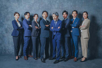 腕組みをするスーツを着た様々な世代の男女