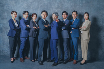 腕組みをするスーツを着た様々な世代の男女