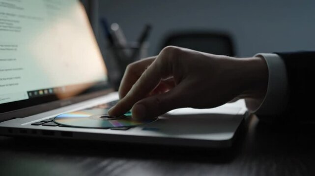 Inserting and ejecting a CD-ROM disc into a laptop computer on a dark desk