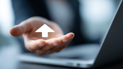 A person's open palm extended over a sleek laptop, with a white, upward-pointing arrow icon floating just over the hand, represents offering, supporting, or holding the key to success.
