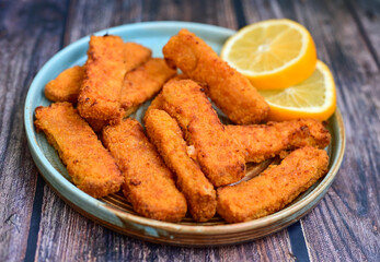 Close up of   Crispy breaded  deep fried fish fingers with breadcrumbs served  with remoulade sauce and  lemon Cod Fish Nuggets on rustic wood table background