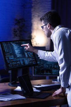 High tech composition. IT specialist reviewing code and system analytics on multiple monitors. Concept of cyber security monitoring, software development, big data processing and network control.